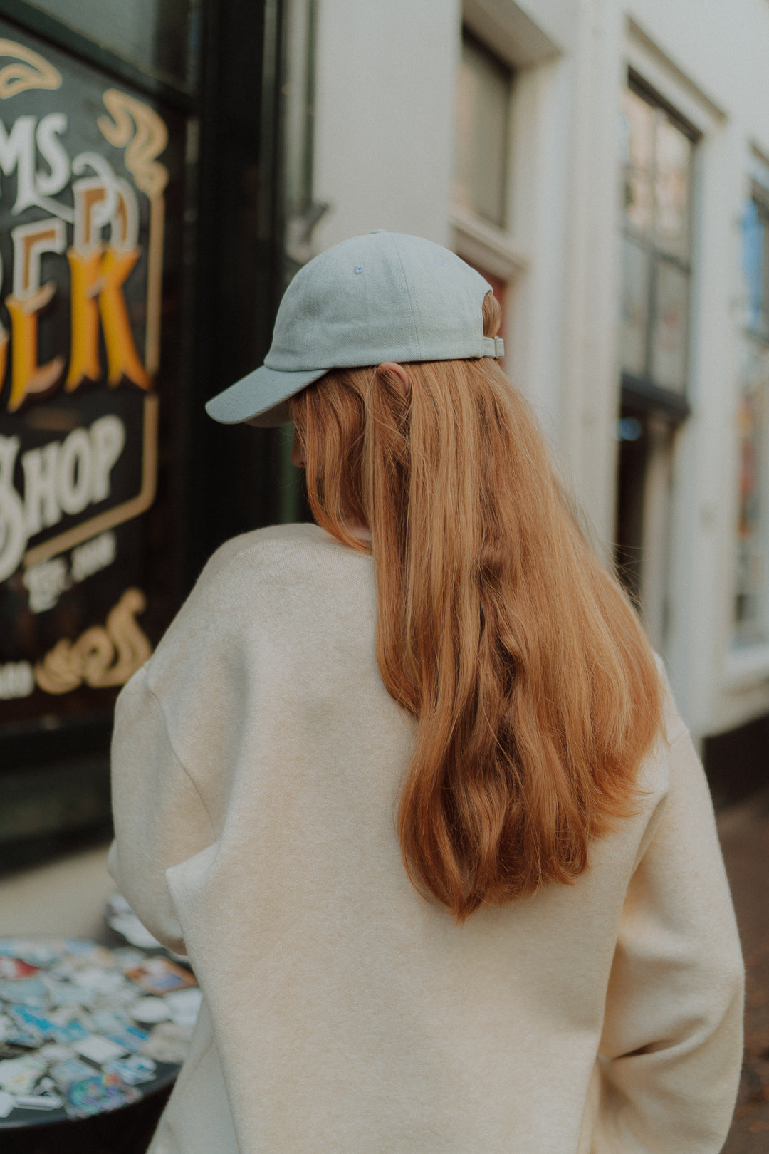 Back view of a girl wearing a baby blue cap and soft neutral knitwear from the Wolvie collection