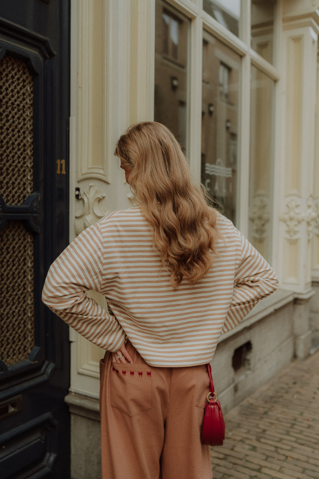 Woman wearing beige striped sweater with wide leg pants in street style setting
