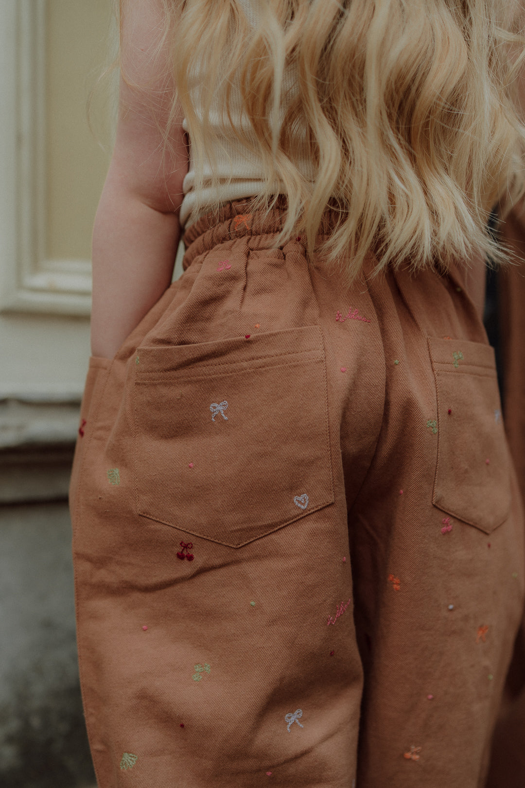 Close-up of brown kids pants with small embroidered details by Wolvie
