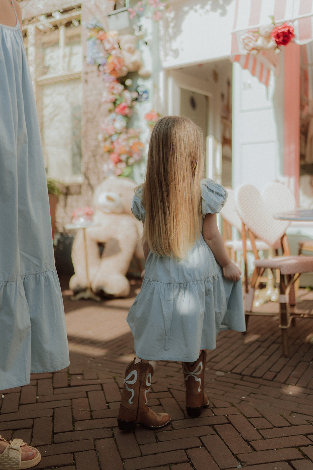 Little girl wearing a light blue puff sleeve dress and cowboy boots