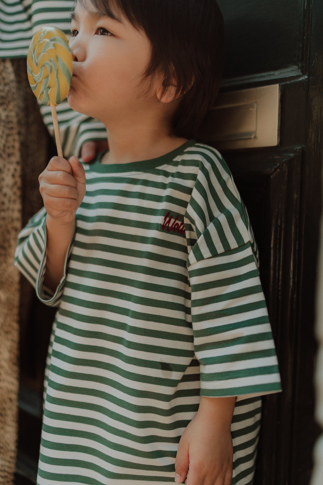 Child wearing matching kids clothes with a green striped oversized shirt and comfy leopard print pants