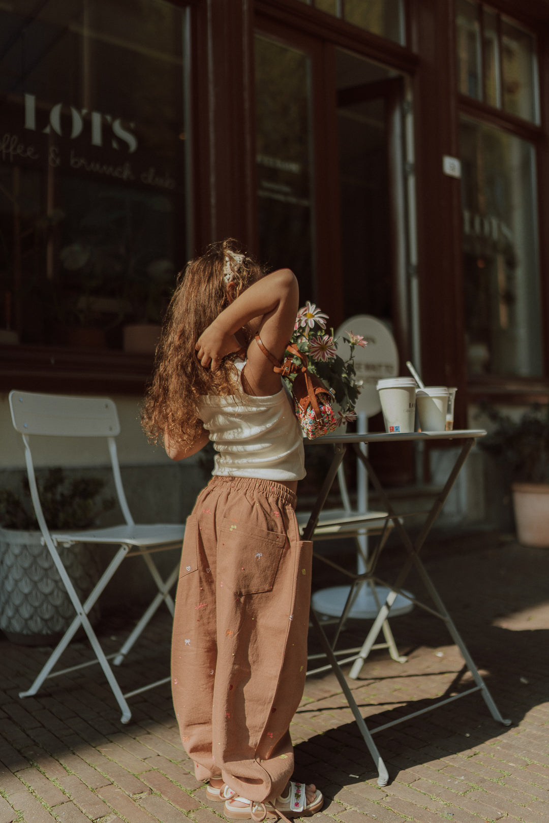 Young girl wearing matching kids clothes with neutral wide leg pants and a cream top in a stylish comfy outfit.