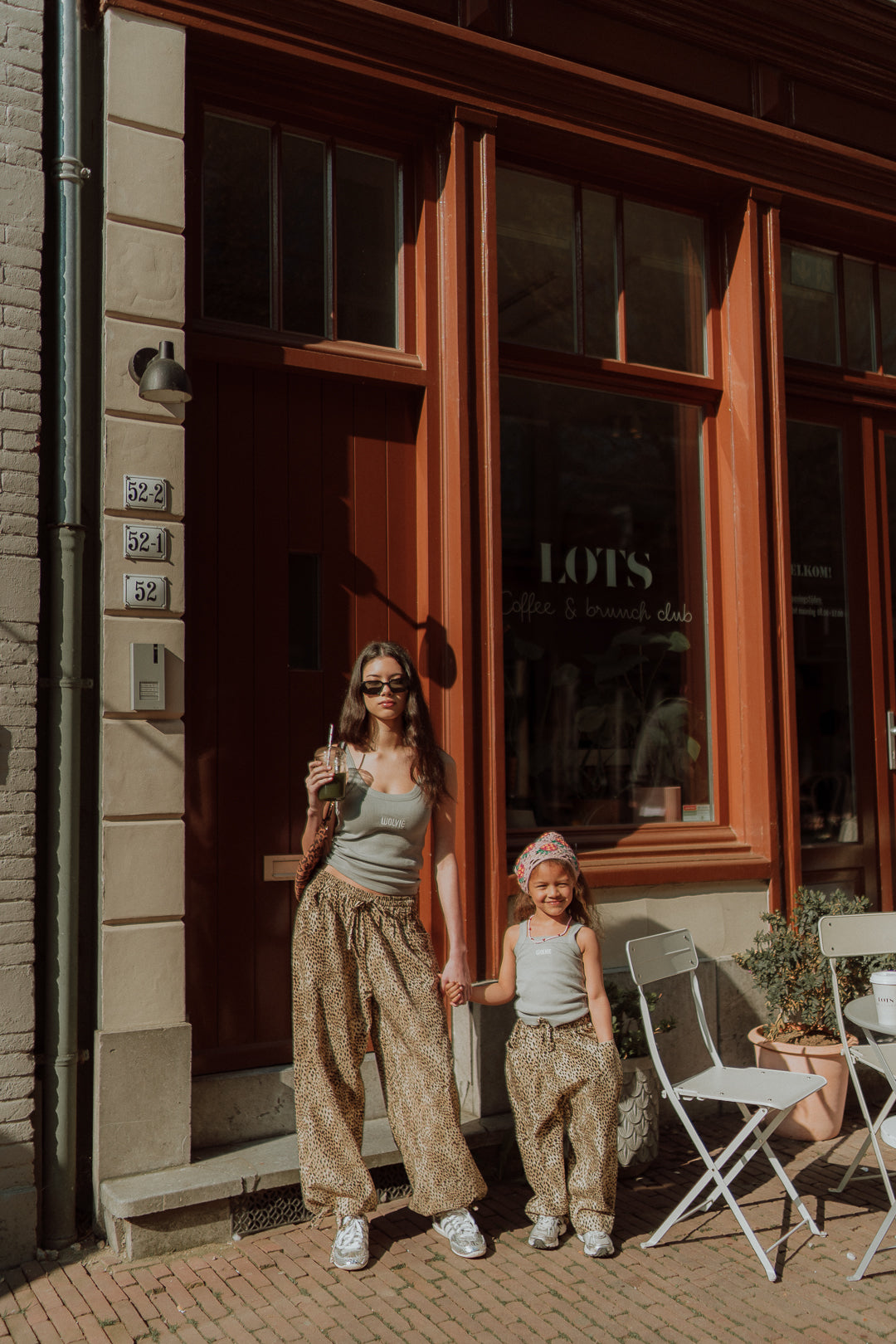 Mother and daughter wearing matching outfits with leopard pants standing in front of a boutique