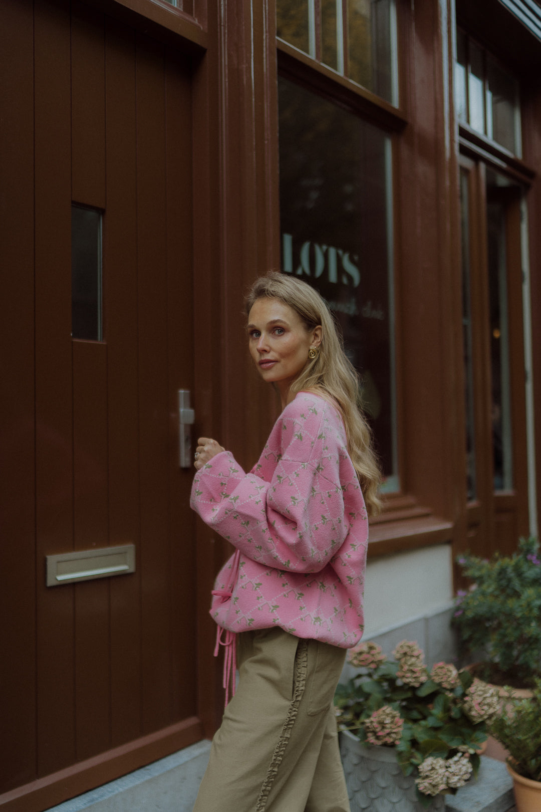 Woman wearing a pink floral sweater and olive pants