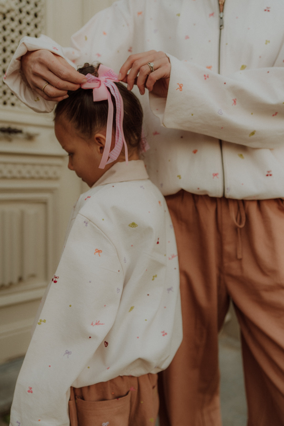 Close-up of mom and daughter wearing matching embroidered outfit with bow detail from Wolvie SS26 collection.