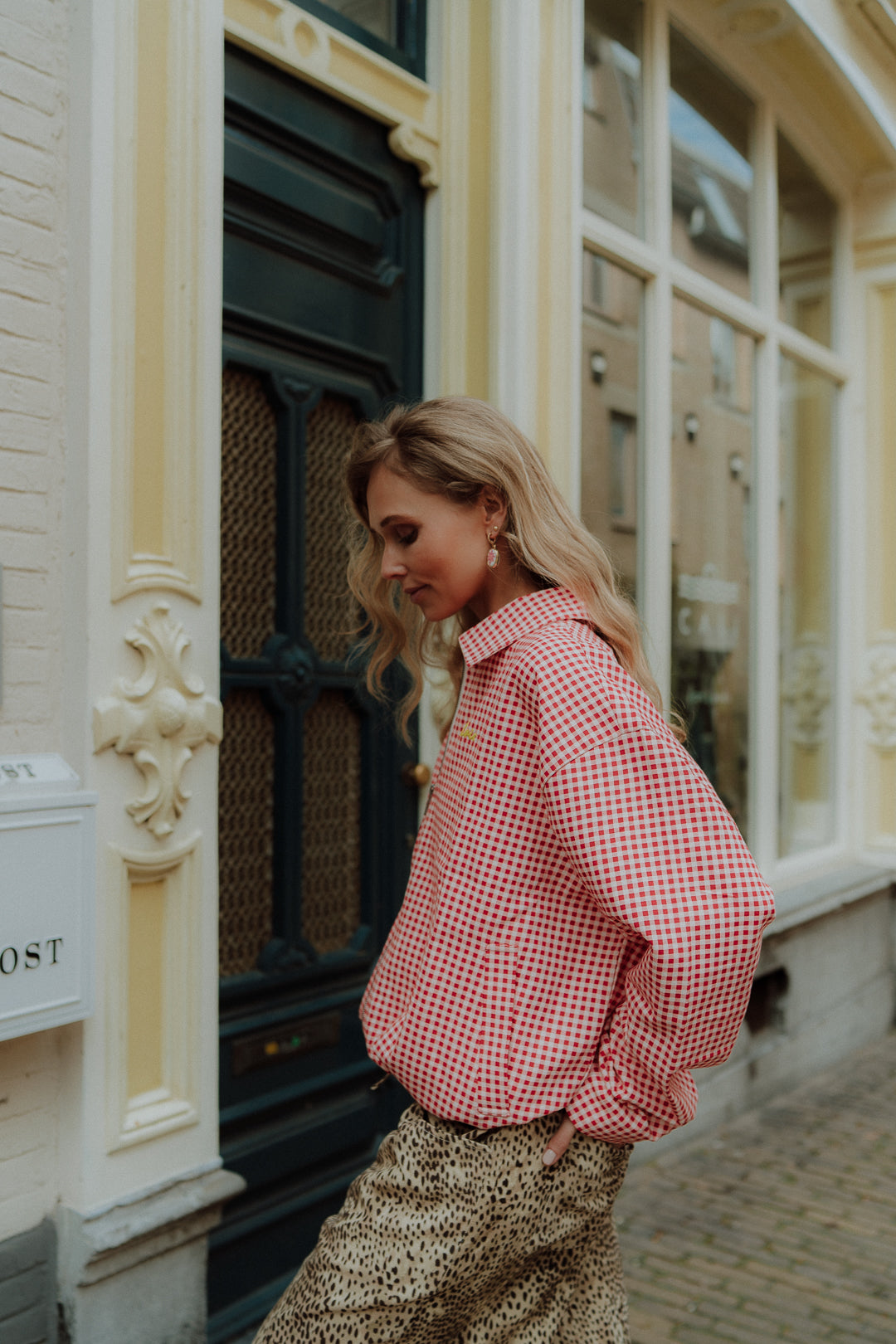 Woman wearing red gingham blouse with leopard print pants in street style setting
