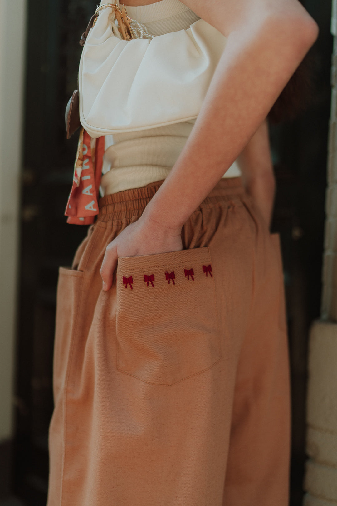 Close-up of women’s brown linen pants with embroidered pocket detail