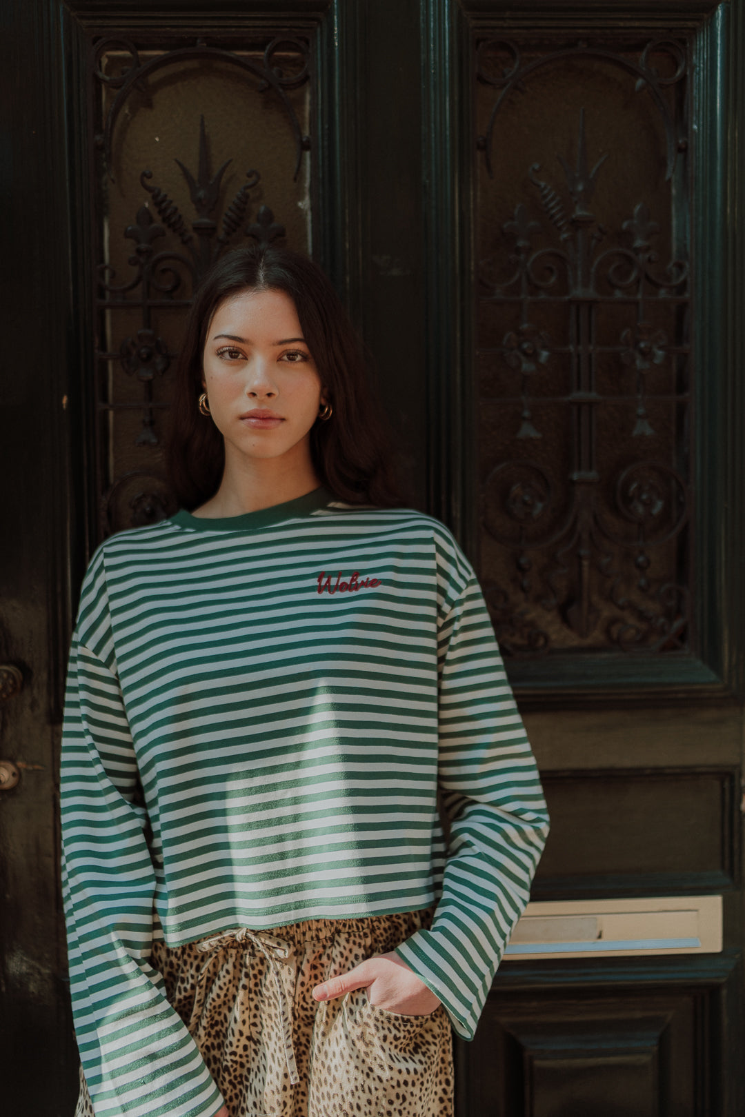 Woman wearing a green striped long sleeve top with leopard print pants.