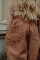 Close-up of brown kids pants with small embroidered details by Wolvie