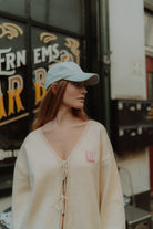 Woman wearing a cream knit cardigan with tie-front detail