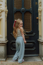 Girl wearing blue pants and sleeveless top standing in front of a door in street style outfit.