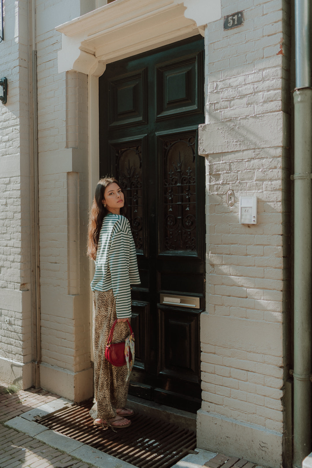 Girl wearing green striped long sleeve top with leopard print pants in street style setting