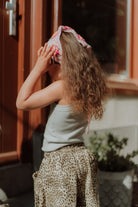 Girl wearing leopard print pants with a light top and headscarf in a stylish summer outfit