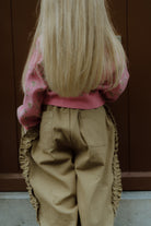 Back view of a young girl wearing a pink floral cardigan and pants.