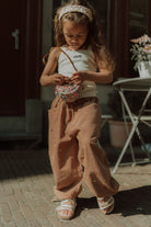 Girl wearing a summer outfit with wide leg pants, a white top and colorful crossbody bag