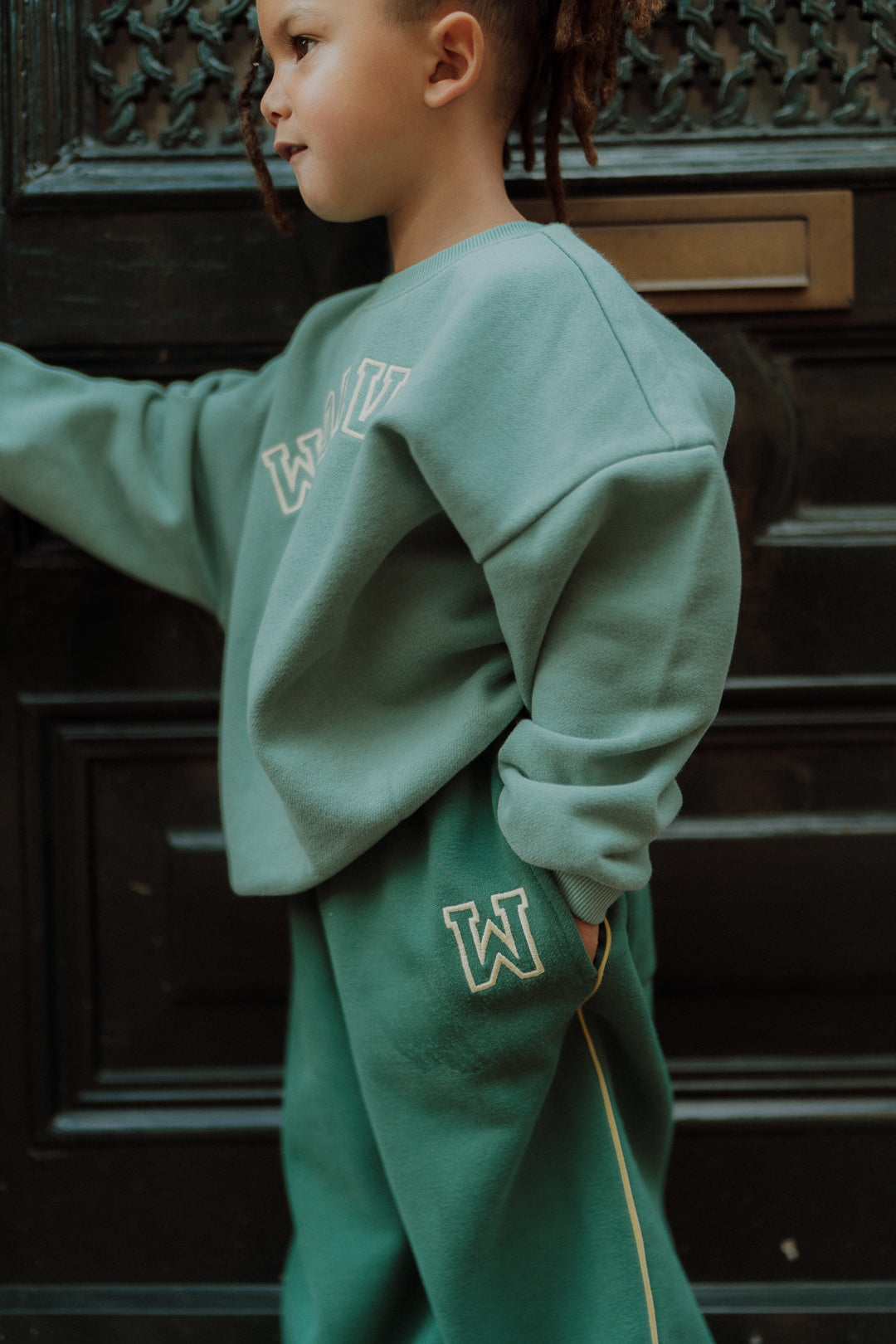 Child wearing a sage green sweatshirt and matching sweatpants 