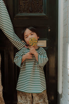 Kid wearing a green striped oversized top with leopard print pants as a matching outfit