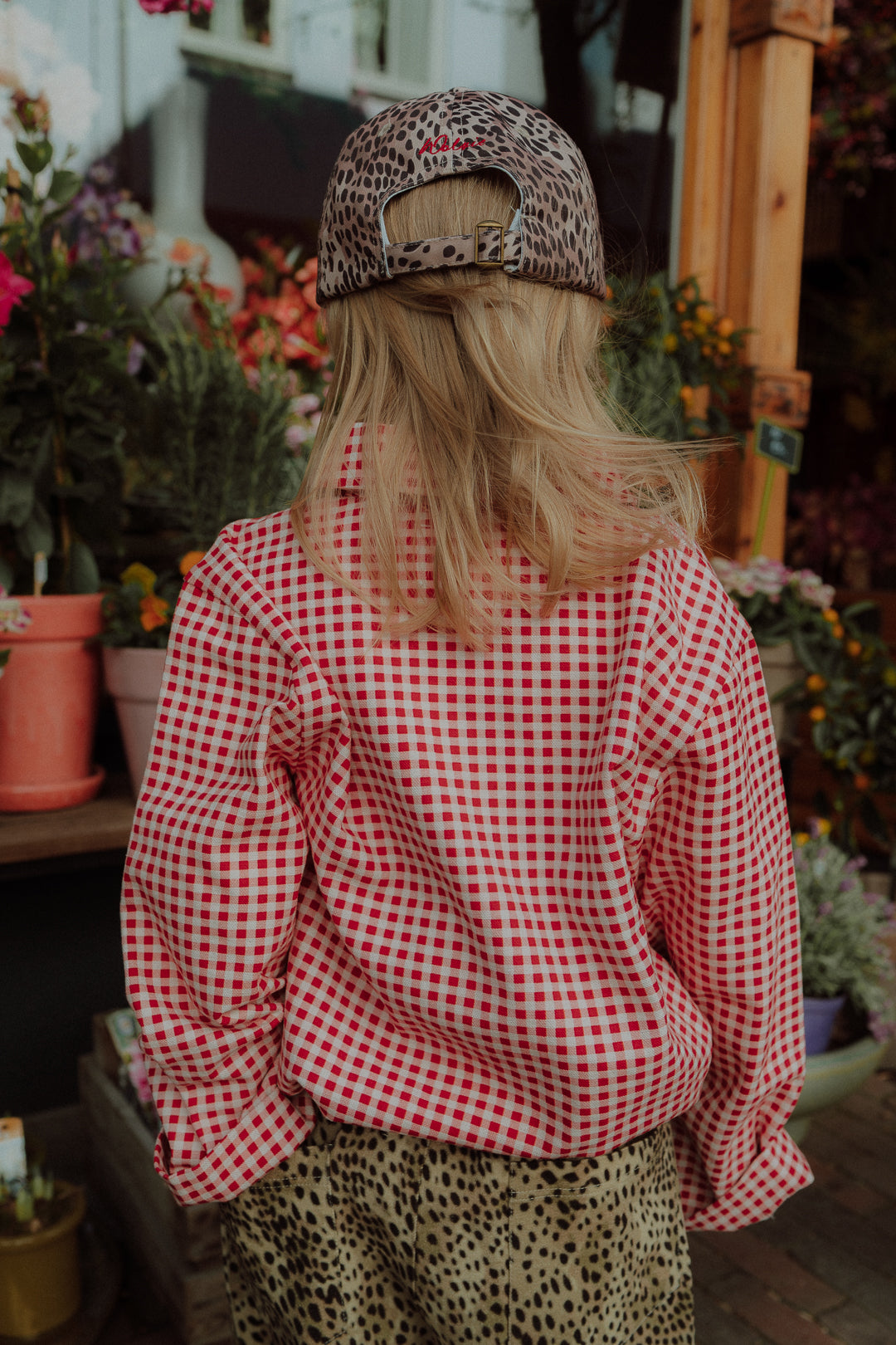 Girl wearing red checkered shirt with leopard print cap and casual outfit styling