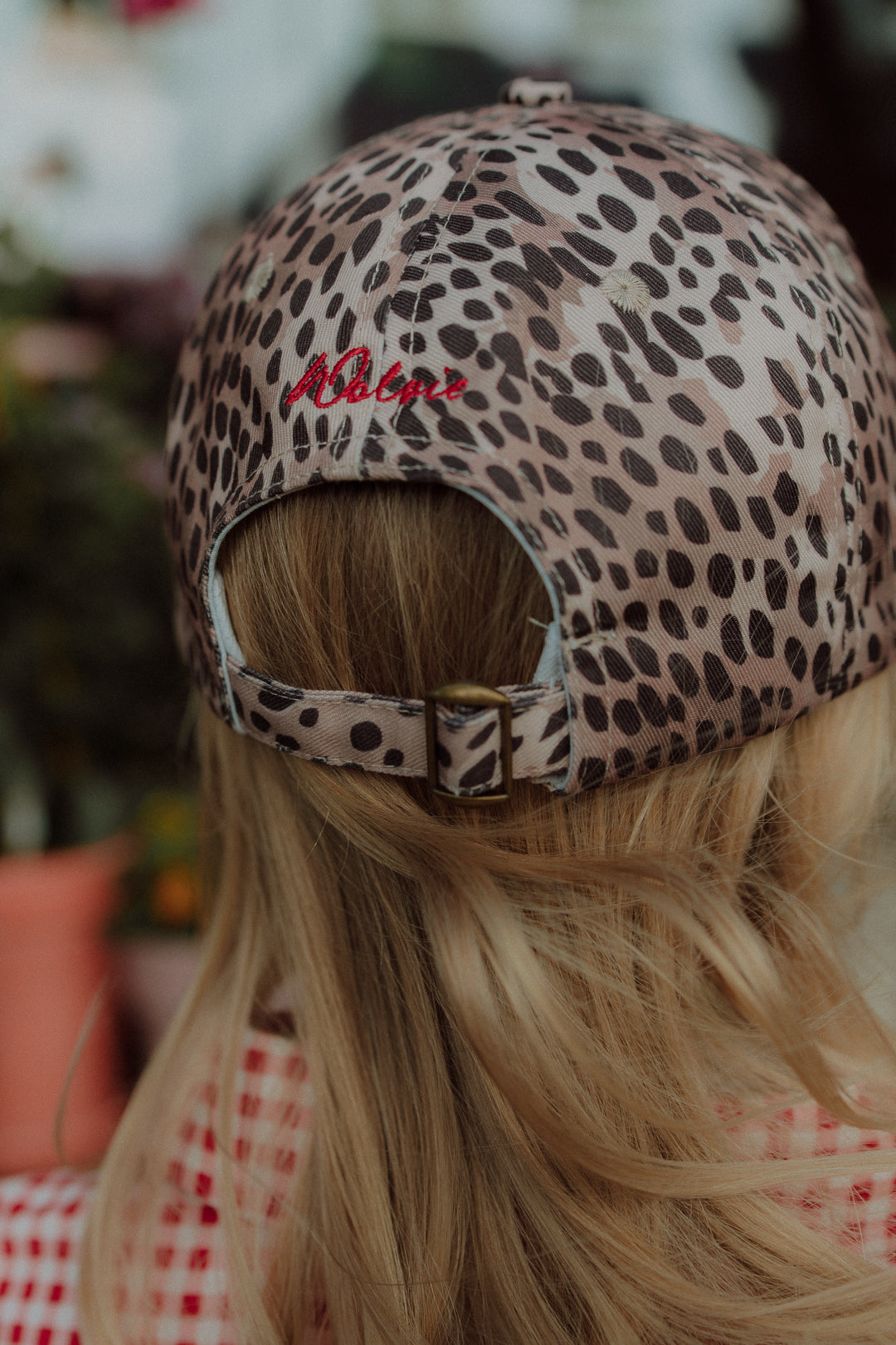 Back view of a child wearing a leopard print cap by Wolvie in a summer setting