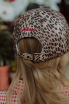 Back view of a child wearing a leopard print cap by Wolvie in a summer setting