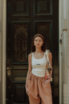 Woman wearing matching clothes with a cream tank top and neutral oversized pants in a comfy stylish outfit.