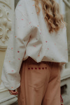 Woman wearing matching clothes with an oversized cream sweater and wide leg pants in a comfy stylish outfit.