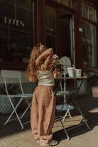 Young girl wearing matching kids clothes with neutral wide leg pants and a cream top in a stylish comfy outfit.