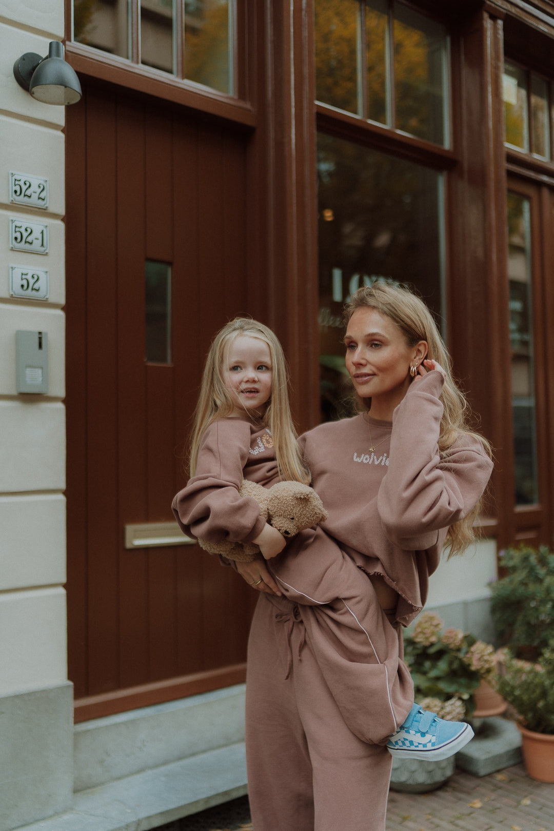 Woman holding a young girl while both wear matching outfits