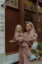 Woman holding a young girl while both wear matching outfits