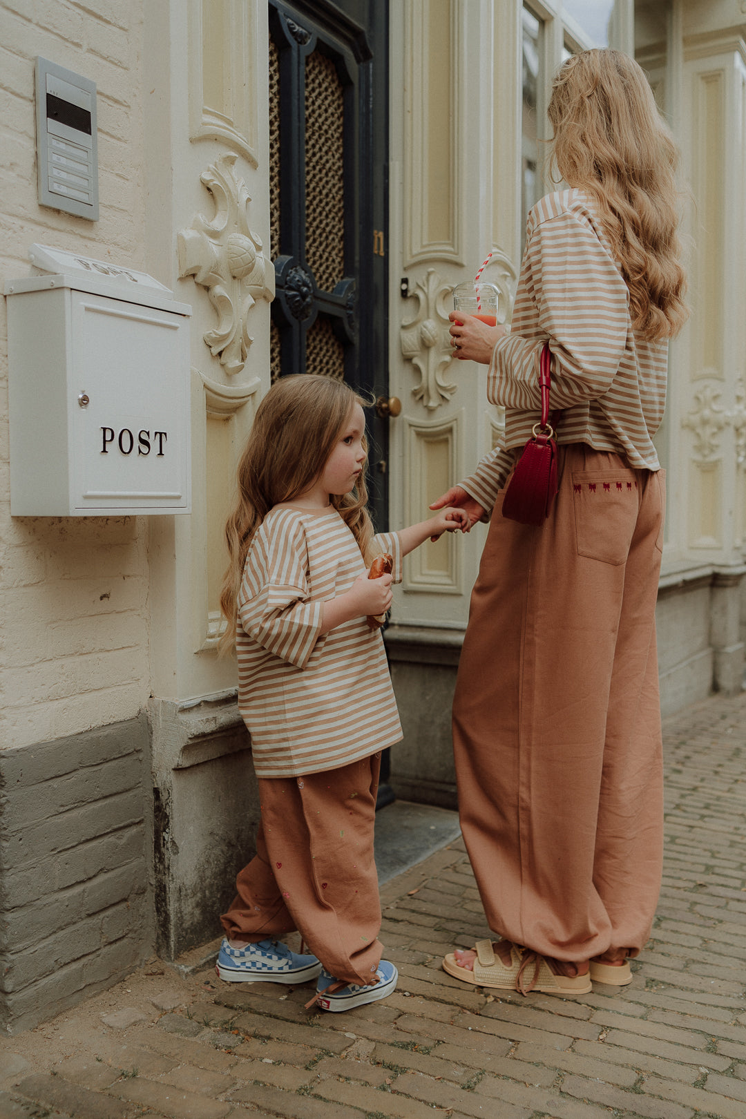 Matching mom and child outfit with camel pants and striped tops in street style setting