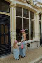 Matching mom and daughter blue outfit with pink caps in street style setting