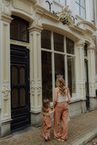 Mother and daughter wearing matching brown outfits walking together in front of a boutique