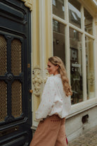 Woman wearing a matching mom outfit with embroidered sweater and brown pants walking in the city