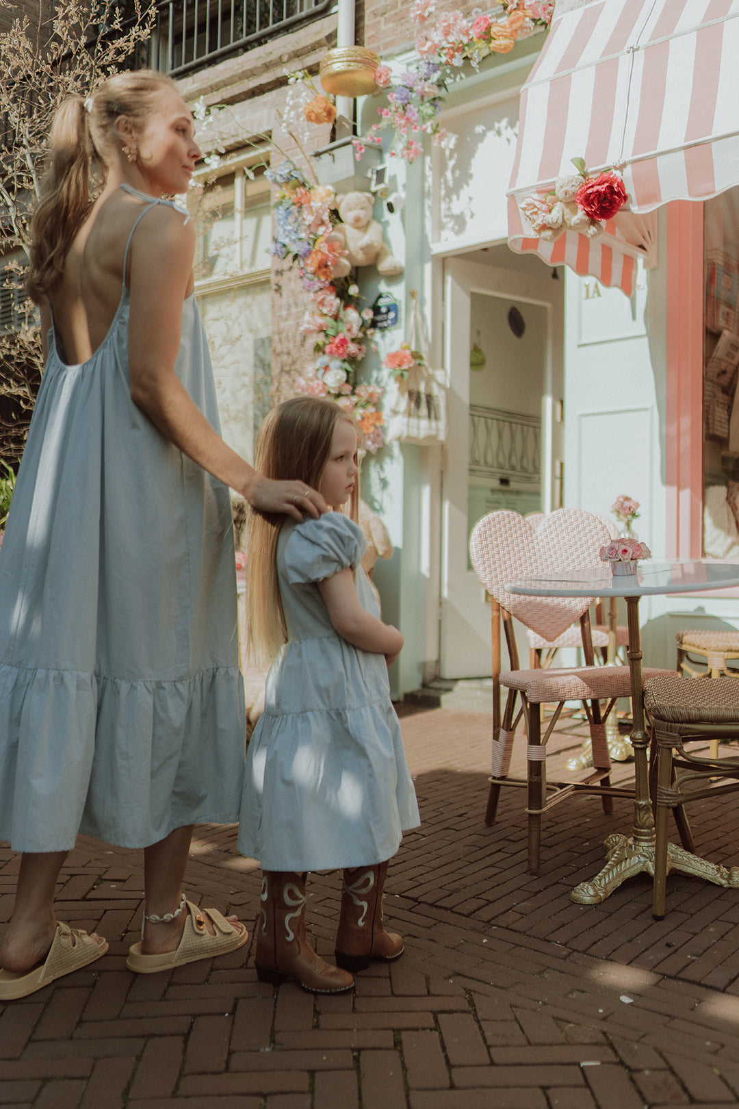 Mother and daughter wearing matching light blue dresses and cowboy boots outside