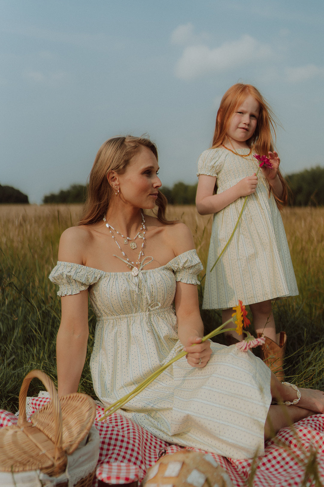 Mother and daughter wearing matching cream summer dresses during a picnic