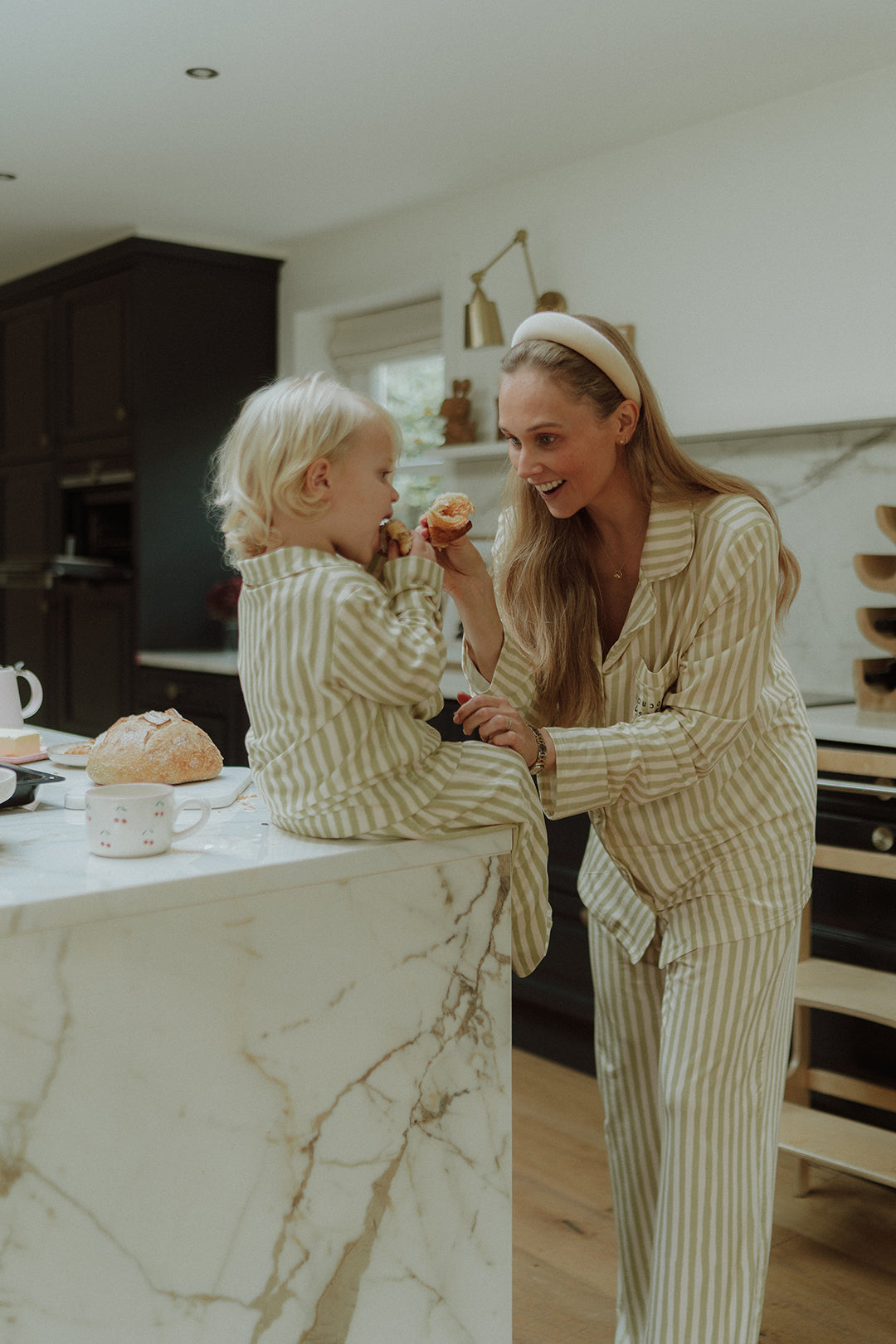 Mother and child wearing matching beige striped pajamas together 