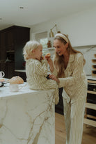 Mother and child wearing matching beige striped pajamas together 
