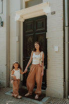 Mother and daughter wearing matching neutral outfits with wide leg pants outdoors