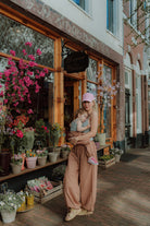 Mother holding toddler wearing matching outfit standing in front of flower shop with colorful flowers lifestyle fashion