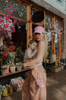 Mother holding toddler wearing matching outfit in front of flower shop lifestyle fashion look