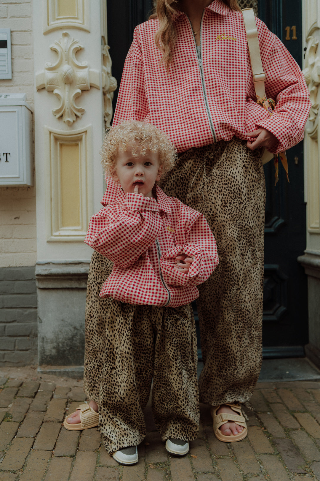 Matching mom and child outfit with red checkered top and leopard pants full body look