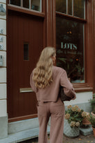 Woman wearing a mauve lounge set viewed from the back outside