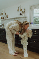 Mother and child wearing matching beige striped pajamas