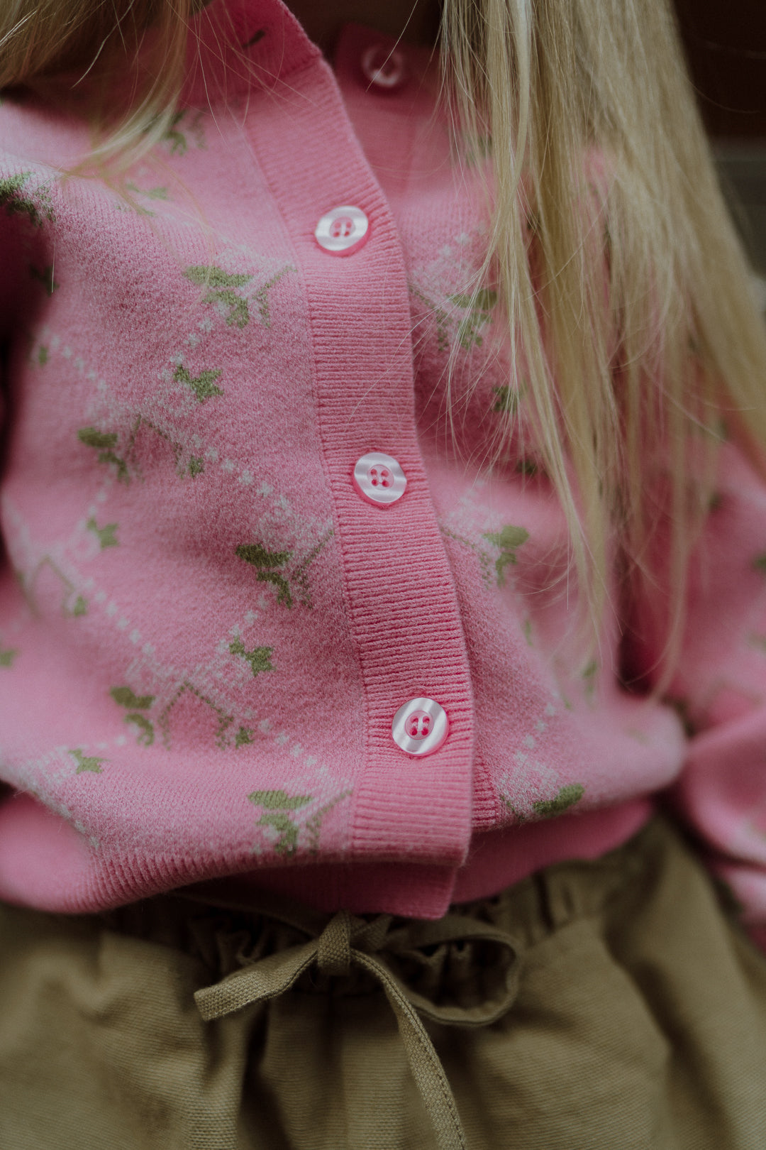 Close-up of a pink floral knit cardigan paired with beige drawstring pants.