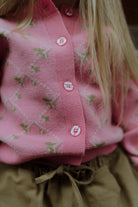 Close-up of a pink floral knit cardigan paired with beige drawstring pants.