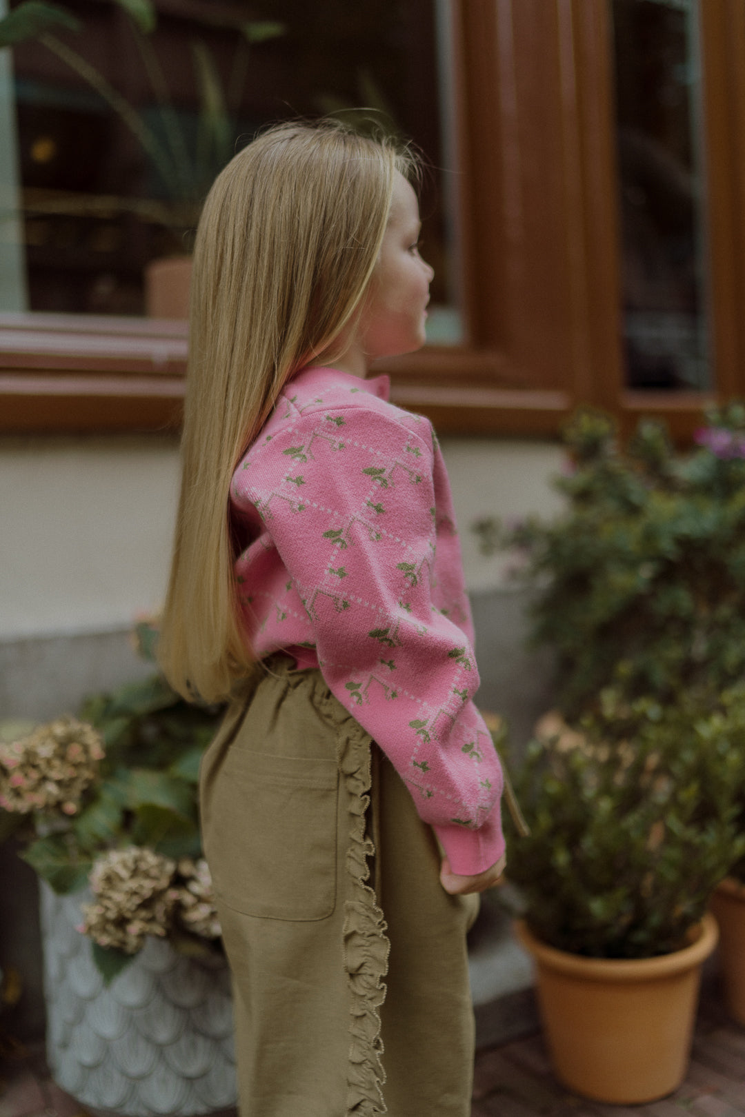 Girl in a pink floral sweater and olive ruffle-detail pants