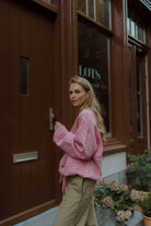 Woman wearing a pink floral sweater and olive pants