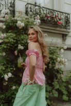 Woman wearing a pink off-shoulder top and green striped pants