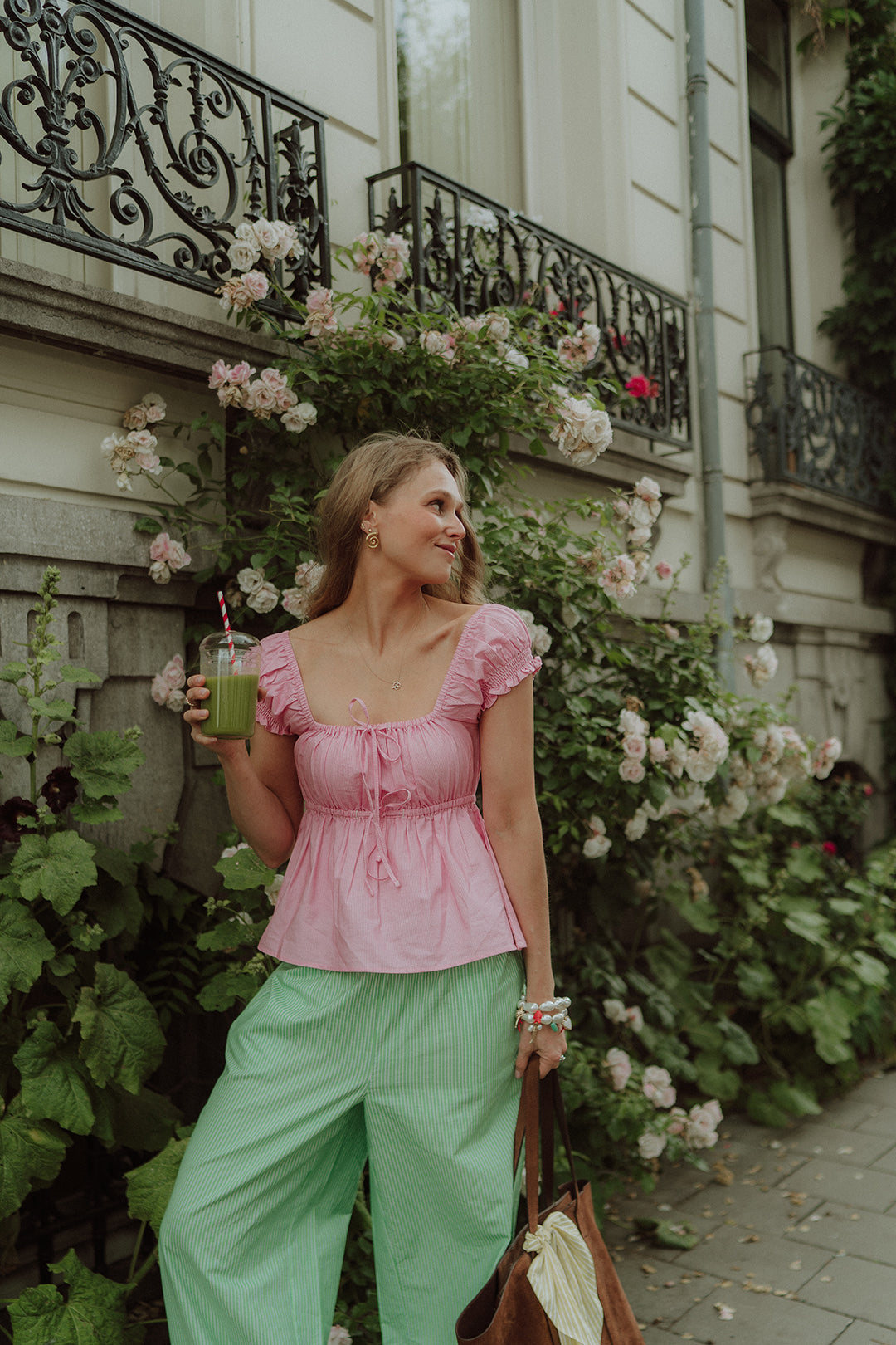 Woman wearing a pink blouse and green striped pants 