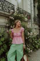 Woman wearing a pink blouse and green striped pants 